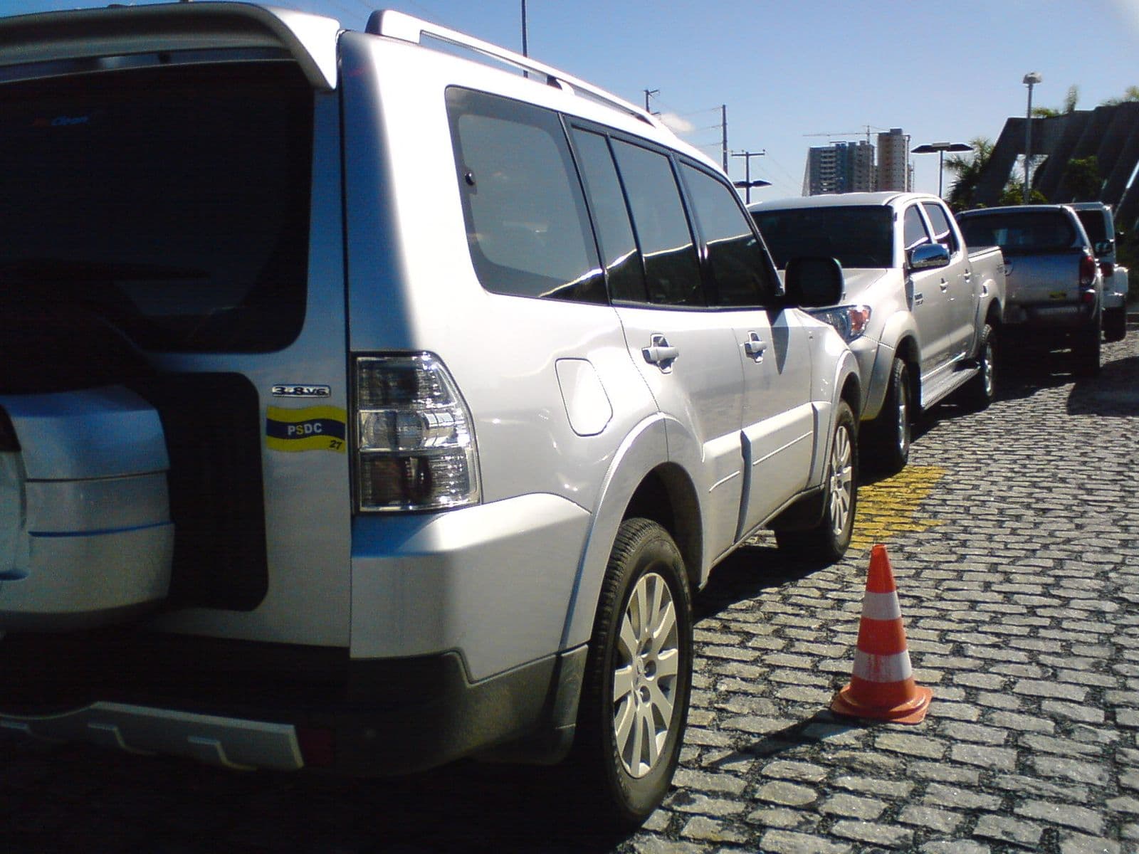 Veículos apreendidos estacionados lado a lado em um pátio com calçamento de pedra