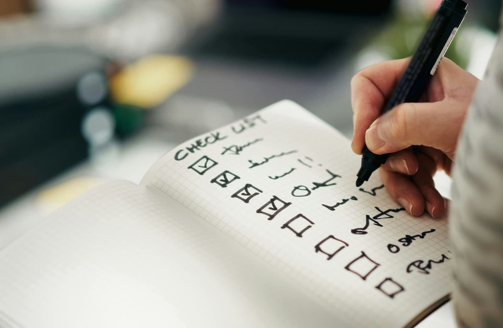 Mão marcando itens de uma lista de verificação em um caderno